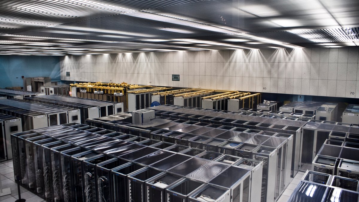 Devasa süper bilgisayar sunucu kabinleri ve fiber optik ışıklandırma altında yapay zeka eğitim kümesi